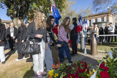 photo de trois jeunes femmes qui déposent des roses devant le monument aux morts - Agrandir l'image 20 sur 38, fenêtre modale