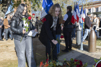 photo de deux jeunes femmes qui déposent une rose devant le monument aux morts - Agrandir l'image 21 sur 38, fenêtre modale