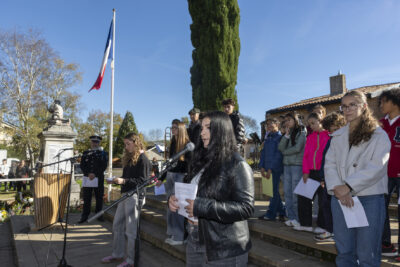 photo d'une jeune qui parle au micro, elle tient une feuille dans ses mains, on voit d'autres jeunes à côté - Agrandir l'image 33 sur 38, fenêtre modale