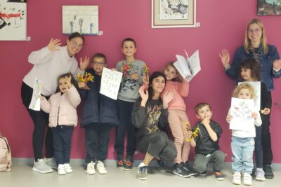 Photo d'enfants et adultes contre le mur en salle qui sourient pour la photo en montrant des dessins - Agrandir l'image 32 sur 32, fenêtre modale