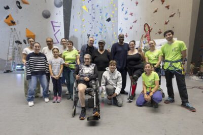 photo de groupe dans la salle d'escalade d'une quinzaine de personnes rassemblées, enfants et adultes, avec une personne en fauteuil au devant - Agrandir l'image 4 sur 68, fenêtre modale