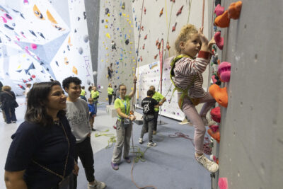 photo d'un enfant qui grimpe au mur sous les yeux de bénévoles et autres adultes - Agrandir l'image 10 sur 68, fenêtre modale