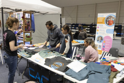 photo d'un stand "CAC" climbers against cancer avec des vêtements en vente répartis sur les tables - Agrandir l'image 12 sur 68, fenêtre modale