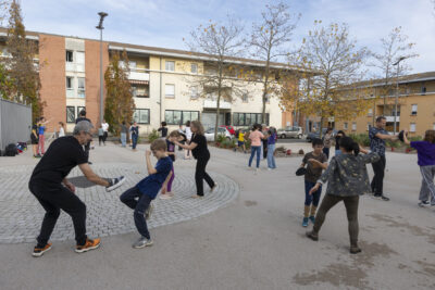 photo d'un atelier self defense sur une place en extérieur, il fait beau, les gens dont des jeunes s'entraînent, un donne un coup de genou, l'autre se protège avec les mains - Agrandir l'image 21 sur 32, fenêtre modale
