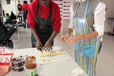 photo de deux femmes qui préparent à manger, une découpe une pâte feuilletée enroulée - Agrandir l'image 29 sur 32, fenêtre modale