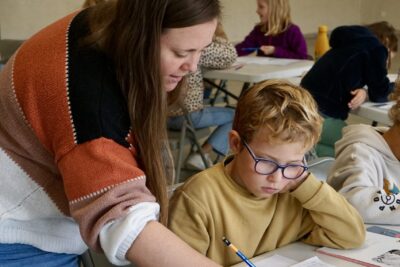 une femme montre à un jeune garçon quelque chose sur sa feuille sur laquelle il a dessiné - Agrandir l'image 2 sur 10, fenêtre modale