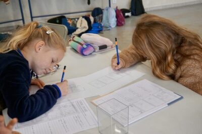 deux jeunes filles dessinent sur une table, sur une feuille blanche avec des cases vides - Agrandir l'image 6 sur 10, fenêtre modale