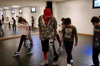 Photo d'enfants dans une salle de danse avec un grand miroir sur le côté, en train de suivre le pas d'un moniteur - Agrandir l'image 9 sur 9, fenêtre modale