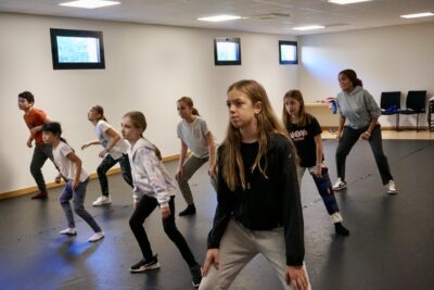 photo d'une dizaine d'enfants qui dansent en ligne dans une salle de danse, les genoux un peu pliés - Agrandir l'image 8 sur 9, fenêtre modale