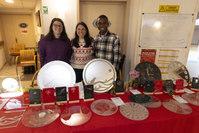 photo de deux femmes et un homme qui posent en souriant derrière un stand de vente de dessous de plat en verre - Agrandir l'image 22 sur 26, fenêtre modale