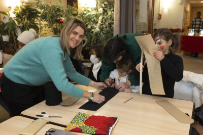 photo de femmes et petites filles qui découpent du tissu sur une table - Agrandir l'image 25 sur 26, fenêtre modale