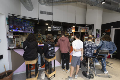 une dizaine de jeunes rassemblés au bar, vus de dos, il y a un écran avec un jeu rétro en cours - Agrandir l'image 14 sur 32, fenêtre modale