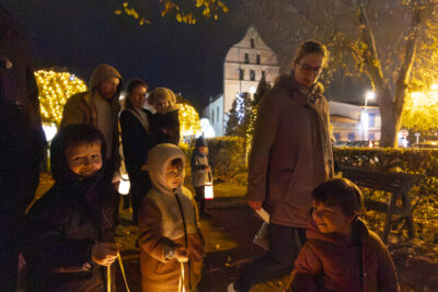 trois enfants avec des adultes, qui marchent avec leurs lampions en souriant, dans un parc de nuit - Agrandir l'image 13 sur 20, fenêtre modale