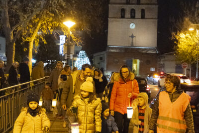 les familles marchent sur un trottoir large avec leurs lampions, on voit la façade de l'église derrière - Agrandir l'image 12 sur 20, fenêtre modale