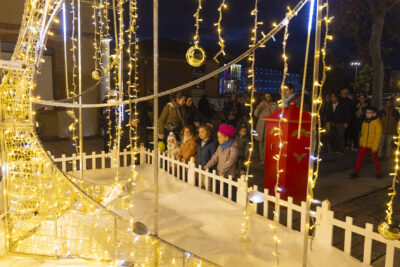 des enfants sont rassemblés devant l'illumination sur le parvis de la mairie, on voit des familles derrière dans la nuit - Agrandir l'image 2 sur 20, fenêtre modale