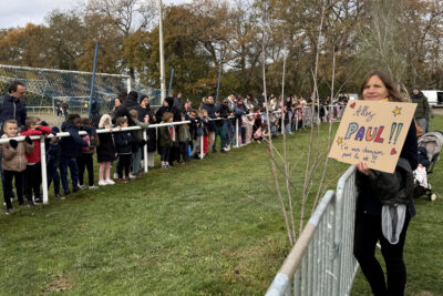 photo des enfants et parents rassemblés pour encourager, sur la droite une femme avec une pancarte "allez Paul" - Agrandir l'image 3 sur 21, fenêtre modale