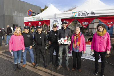 photo de 7 bénévoles rassemblés devant le stand des motards au grand cœur, l'un d'eux tient une figurine à l'effigie du Père Noël à moto - Agrandir l'image 6 sur 12, fenêtre modale