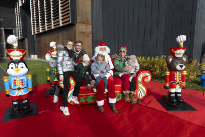 photo d'une famille, un homme et une femme avec trois enfants, qui posent avec le Père Noël et le lutin - Agrandir l'image 7 sur 12, fenêtre modale