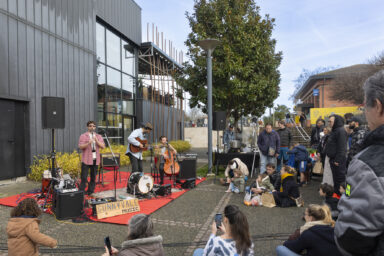 photo du concert de sunnyvale music, trois jeunes hommes en train de jouer clarinette, guitare et contrebasse, devant de nombreuses personnes réunies