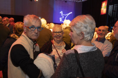 photo d'un groupe de personnes, une femme regarde l'objectif en riant, un homme à côté, la foule derrière eux - Agrandir l'image 12 sur 20, fenêtre modale