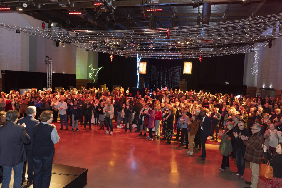 photo de la salle depuis la scène sur laquelle les élus sont rassemblés, la foule réunie dans la salle écoute